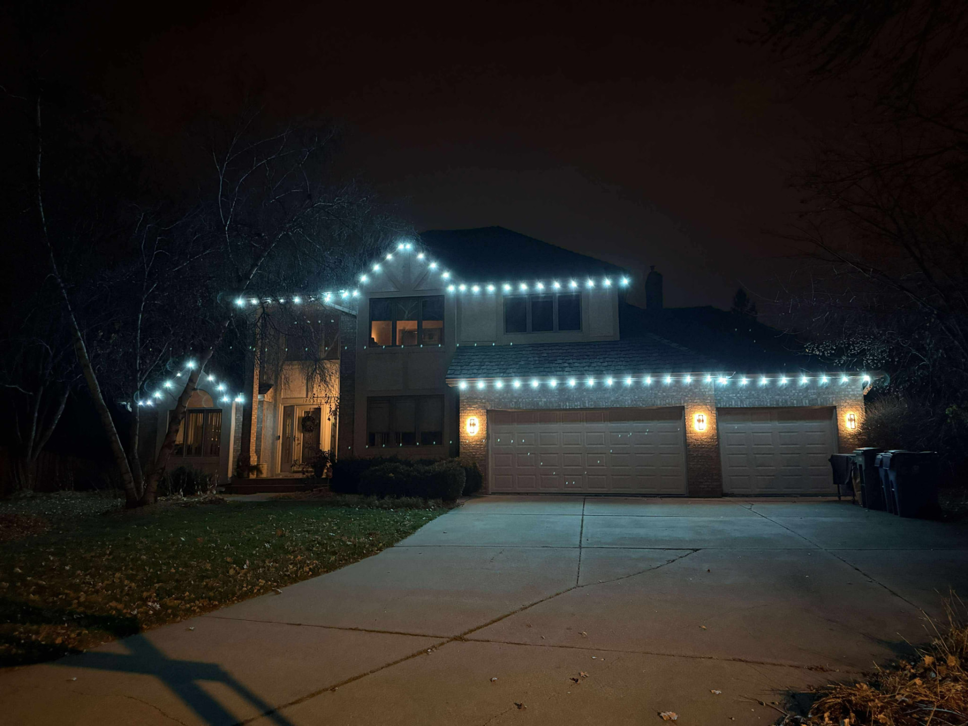 White permanent LED string lights on a stucco home at night