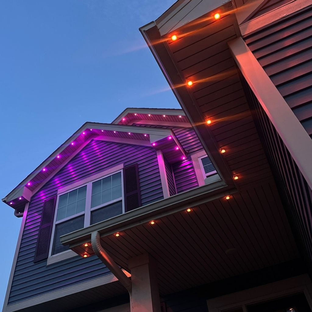 Warm white permanent LED trim lighting on a stone home at dusk