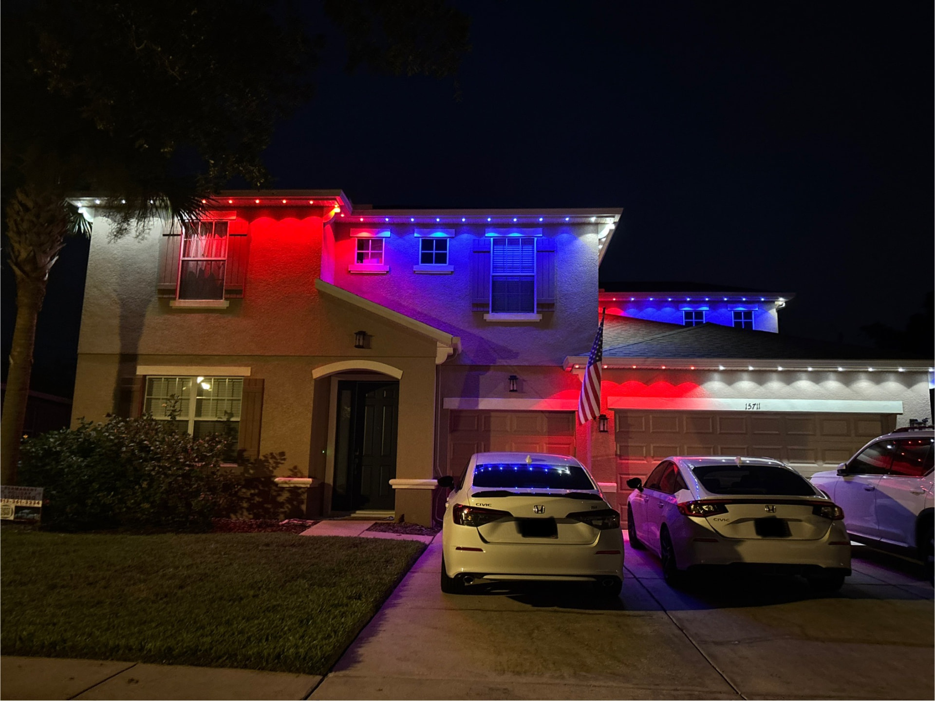 Red, white and blue permanent roofline lights on a two-story home at night